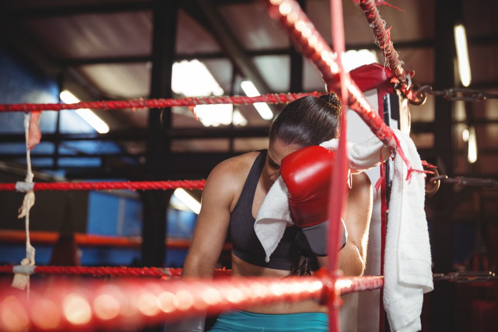 Boxerka sediaca v ringu a utierajúca si tvár do uteráka
