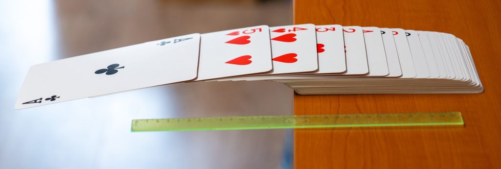 Ten istý pokus s balíčkom kariet, karty prečnievajú mimo stola