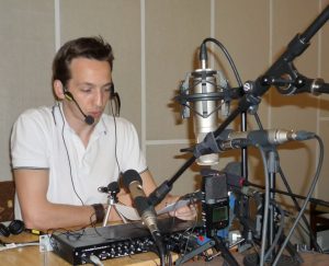 Výskumník sedí za stolom obkolesený rôznymi druhmi mikrofónov