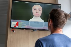 Muž hľadí na obrazovku s virtuálnym asistentom.