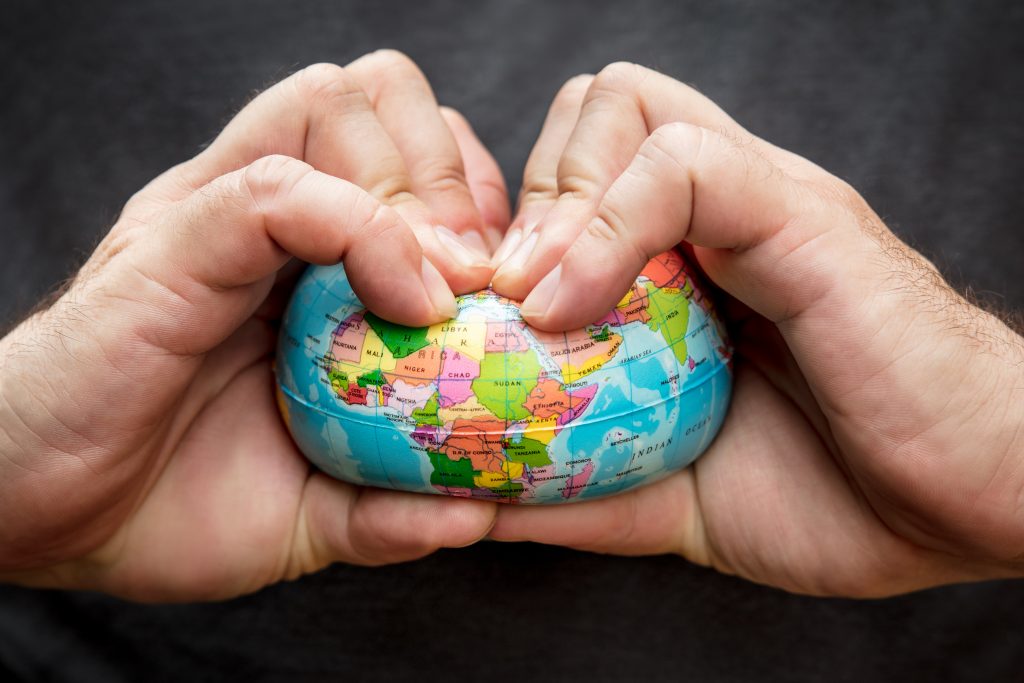 Ruky stláčajúce stresovú loptičku v podobe glóbusu