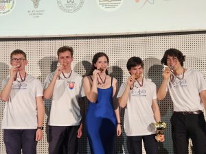 Mladí študenti a študentka pózujú s medailou na spoločnej fotografii