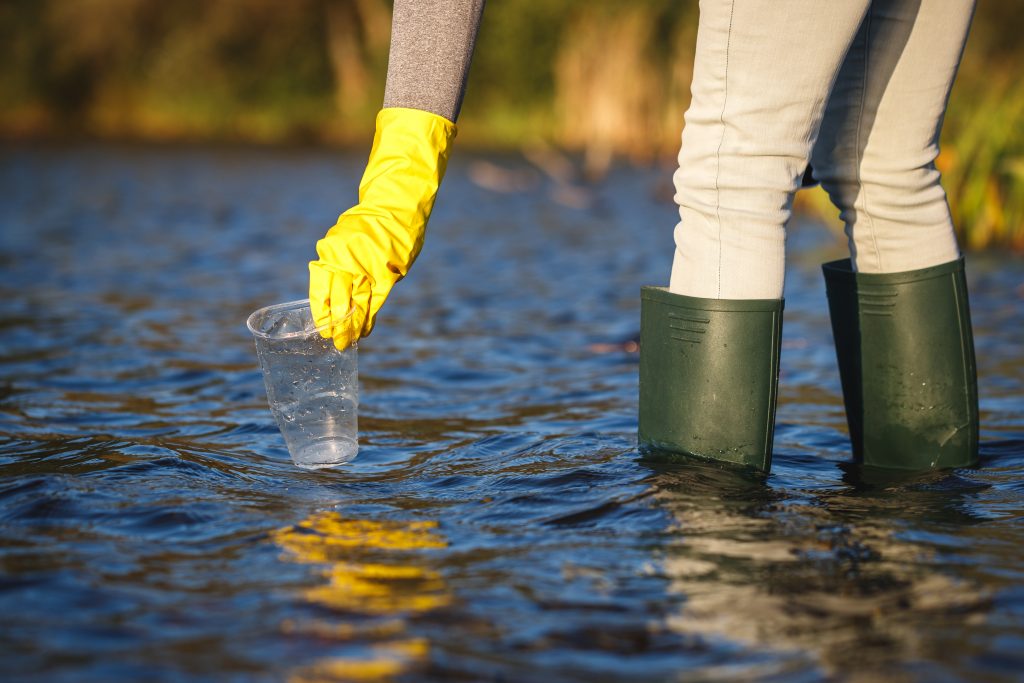 Dobrovoľník zbiera plastový odpad z vody.