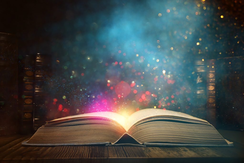 Obrázok otvorenej knihy na drevenom stole s trblietkami