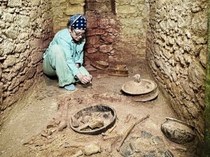 Archeologička pri práci v hrobke. Okolo nej nájdené artefakty