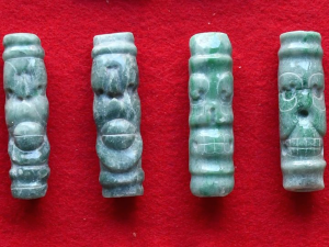 Prívesky zo zeleného kameňa na červenom textilnom pozadí