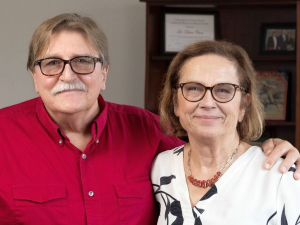 Muž a žena v stredných rokoch pózujú na fotke. Manžel drží manželku okolo ramien.