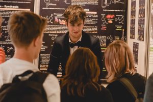 Mladý muž v obleku hovorí s mladými ľuďmi