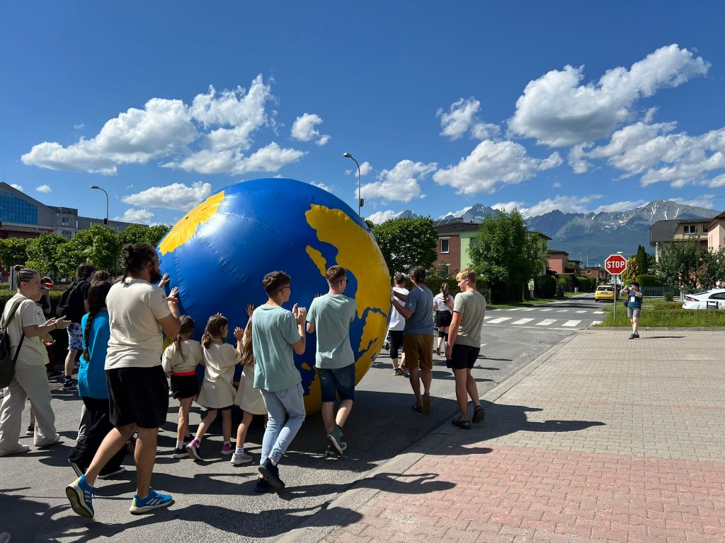 Študenti v rôznom veku kotúľajú po ulici maketu Zeme.