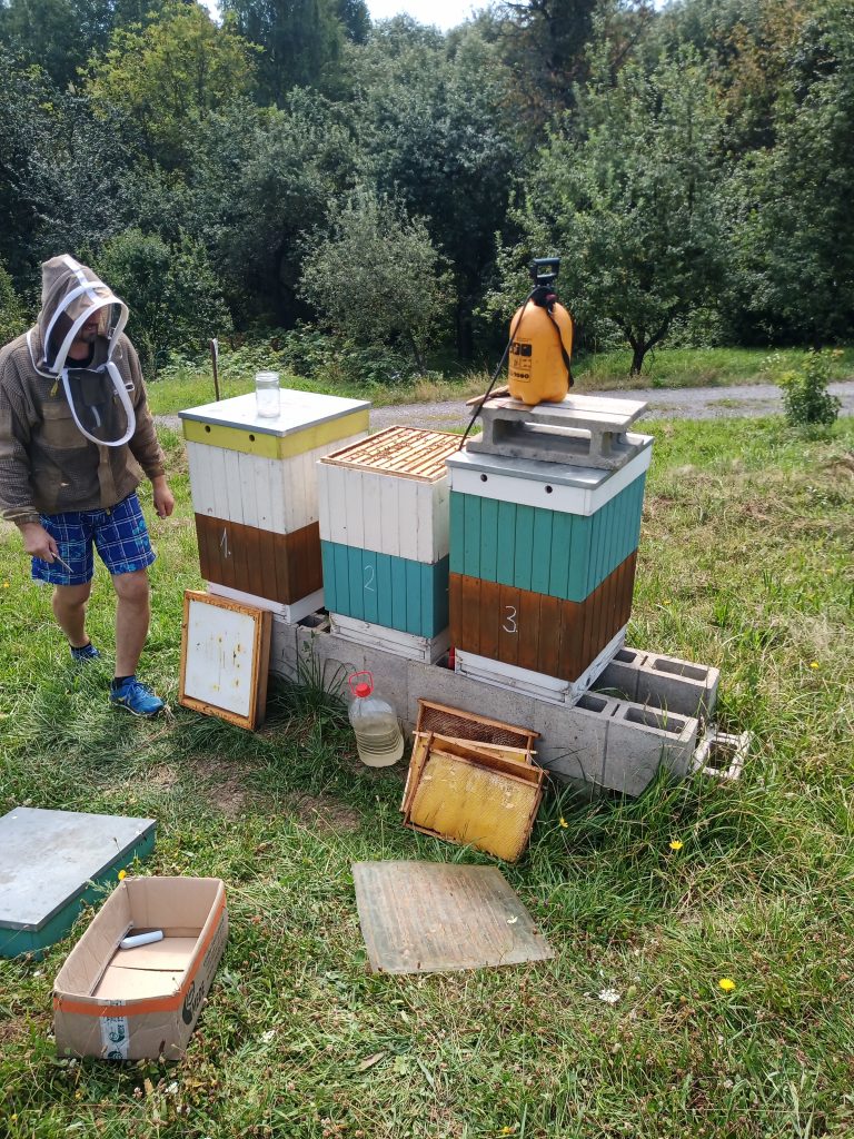 Včelár pracuje pri úľoch s postrekom.