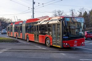 Dlhý červený trolejbus uprostred mesta