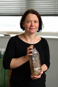 Žena pózuje s kameňom hnedej farby