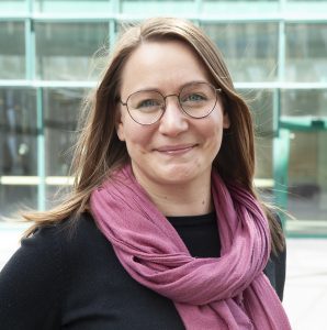 Mladá žena v okuliaroch s ružovou šatkou okolo krku na portrétnej fotografii