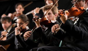 Viacero hudobníkov v orchestri, v popredí huslisti