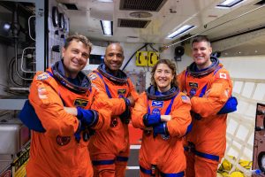 Traja astronauti a astronautka NASA v oranžových kombinézach