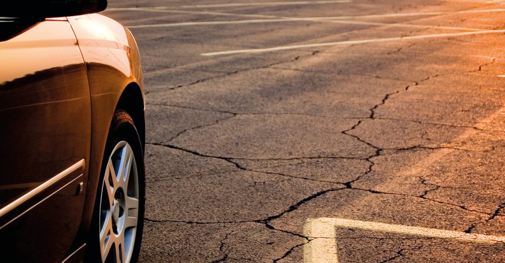 Časť osobného automobilu stojaceho na rozpálenej asfaltovej ploche