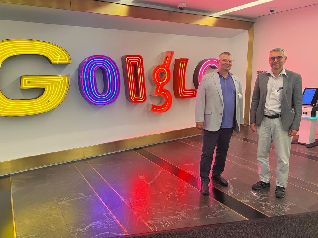 Michal Ries a Ivan Kotuliak v interiéri pred veľkým farebne osvetleným nápisom Google